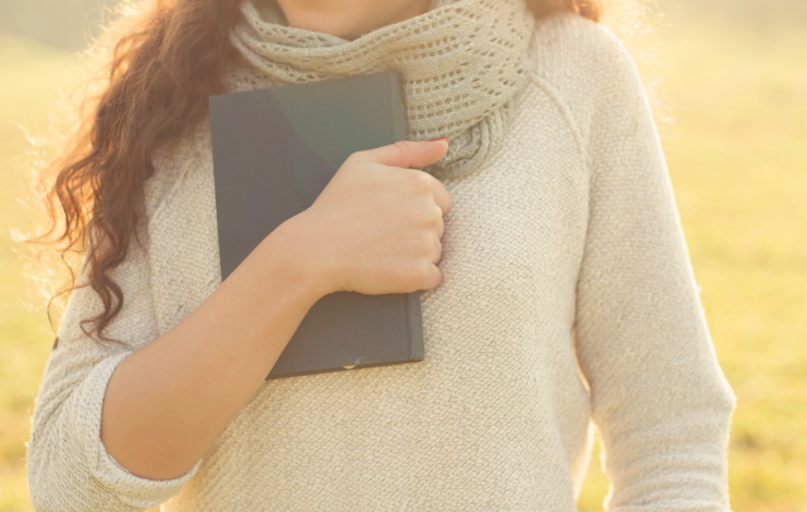 Person in a sweater holding a book to their chest