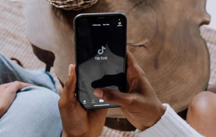 A person's hand holding a phone that is showing the TikTok app