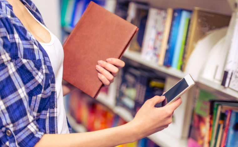 Person in bookstore holding a book and a phone