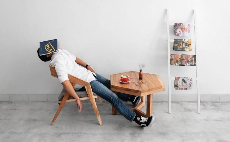 A person asleep in a chair with a book over their face