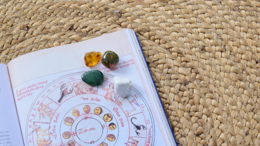 An open book showing a zodiac wheel on a woven rug