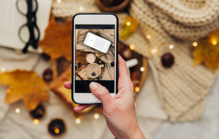 A hand holding a phone showing an open photography app above a flatlay