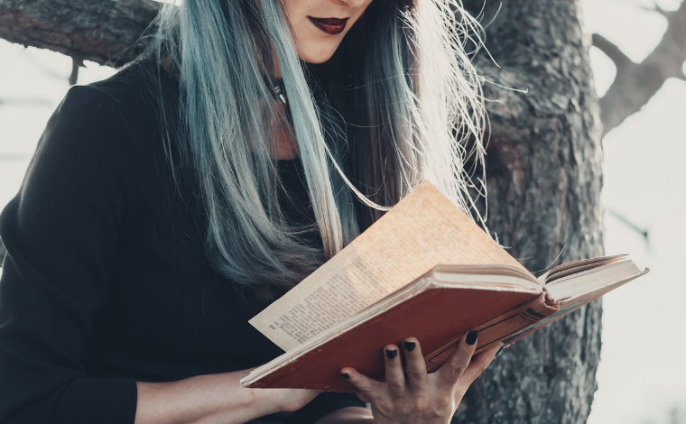A witch reading a book in the woods