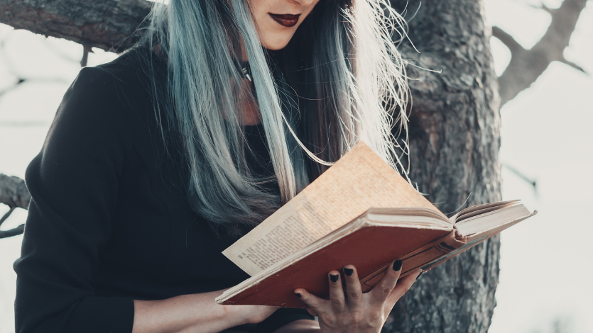 A witch reading a book in the woods