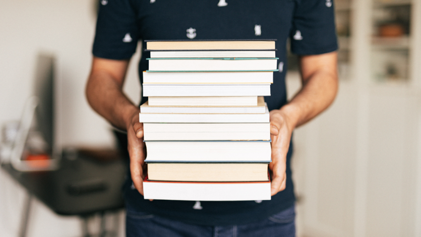 Person holding a stack of books