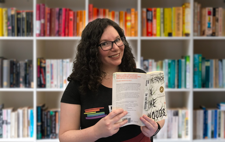 Kelly holding up a book in front of a bookshelf backdrop