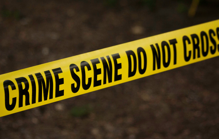 Yellow ribbon reading "Crime Scene Do Not Cross" over dirt