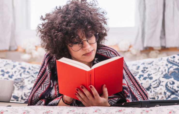 Teen lying down in bed and reading a book