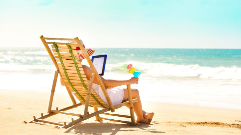 A person reading a kindle on a chair at the beach