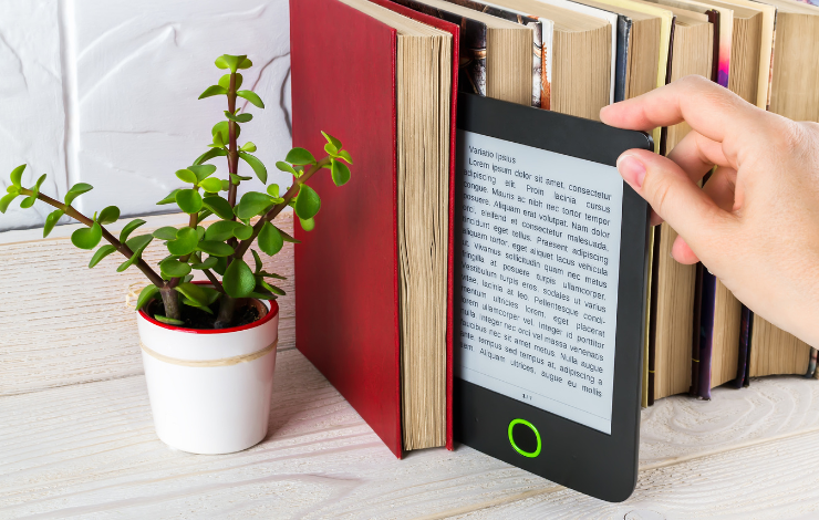 An ereader being pulled out from a row of books