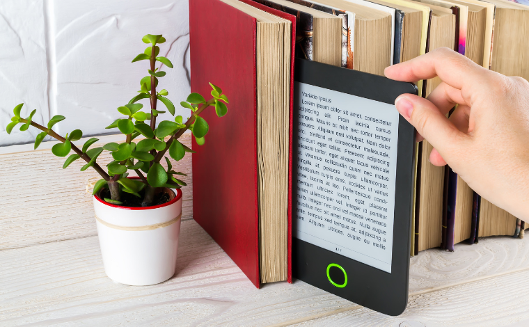 An ereader being pulled out from a row of books