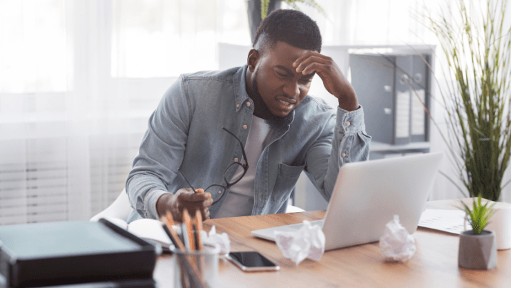 A man sitting in front of a computer looking frustrated