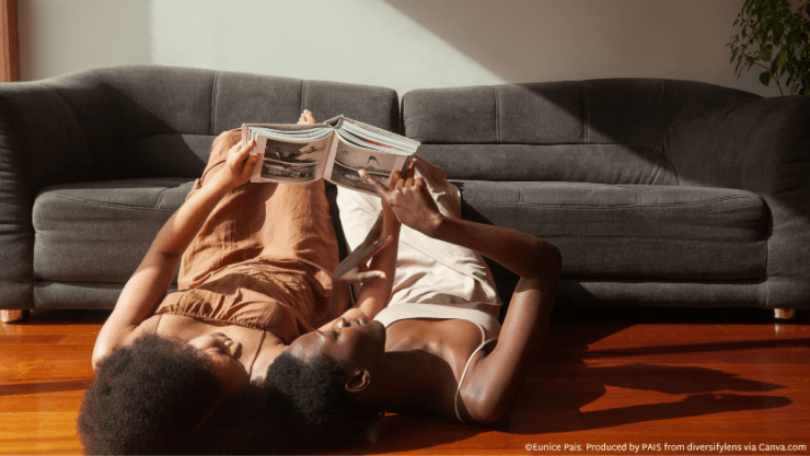 Two women lying on the floor reading a book