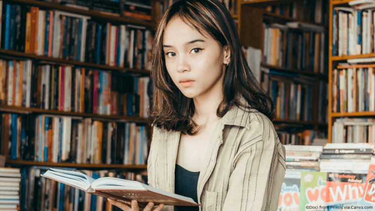 An Asian woman in a bookstore holding open a book