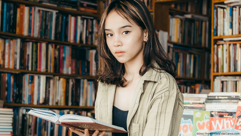 An Asian woman in a bookstore holding open a book