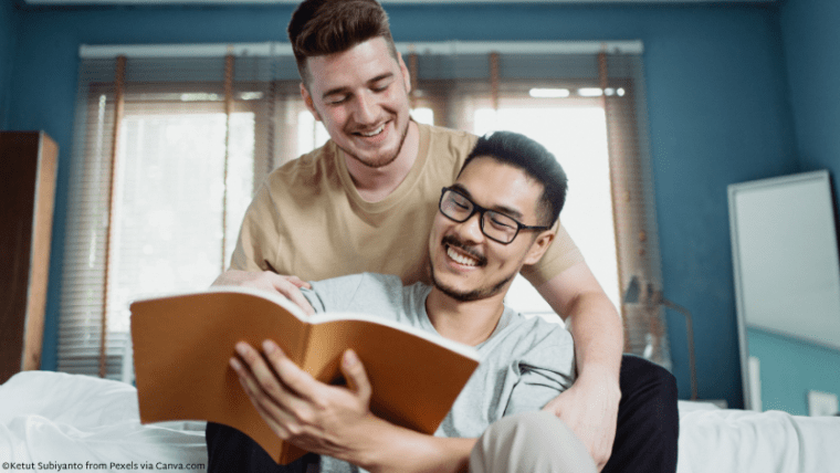 Two men looking at a book together and smiling