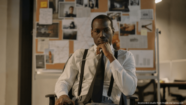 A detective sitting in front of a corkboard of clues