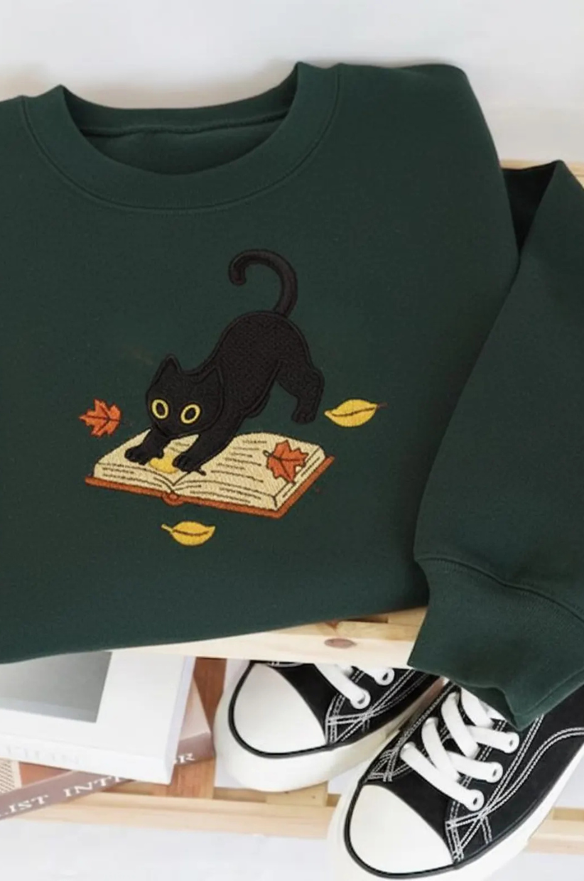 Sweatshirt of a black cat on an open book