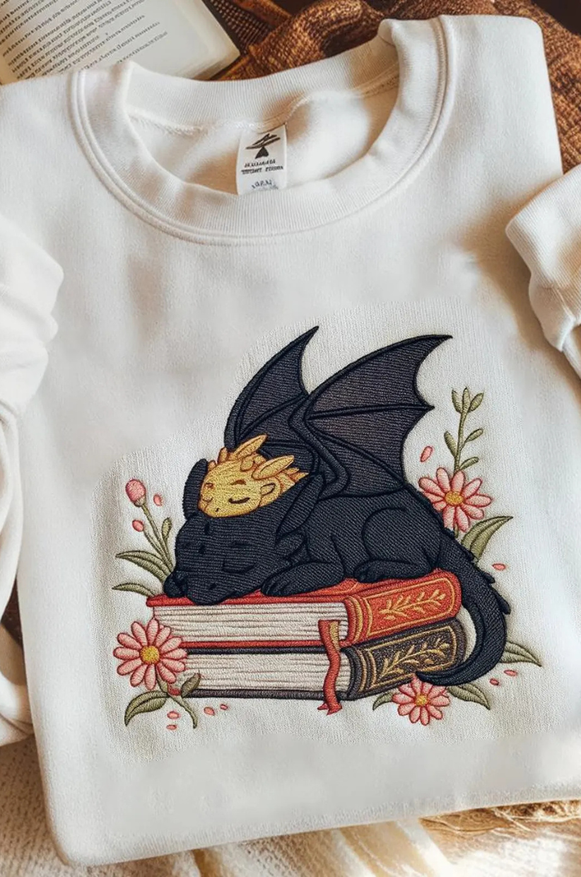 A sweatshirt of two dragons sleeping on a book stack
