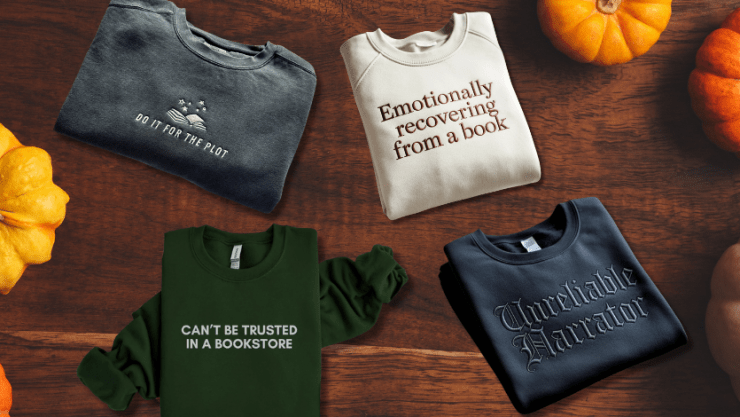 Four bookish sweatshirts on a flatlay of brown wood