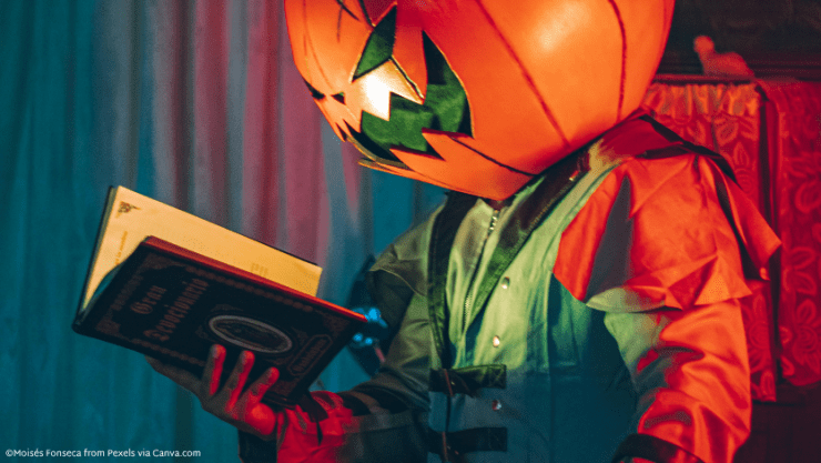 Someone with a pumpkin mask on reading a book