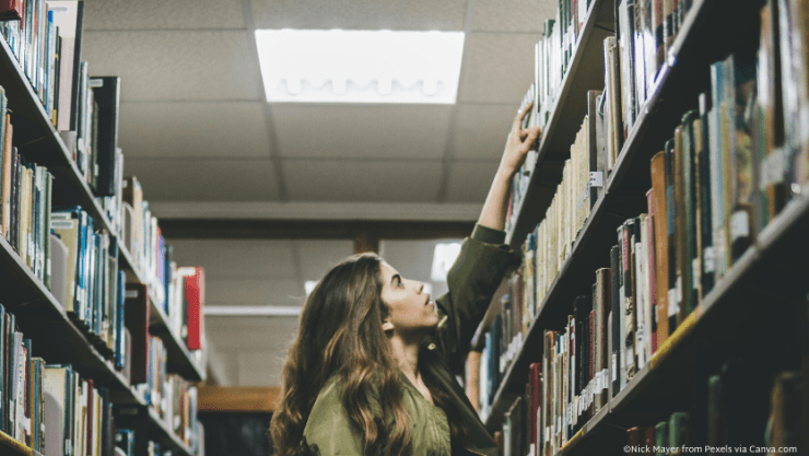 Woman reaching for book on shelf