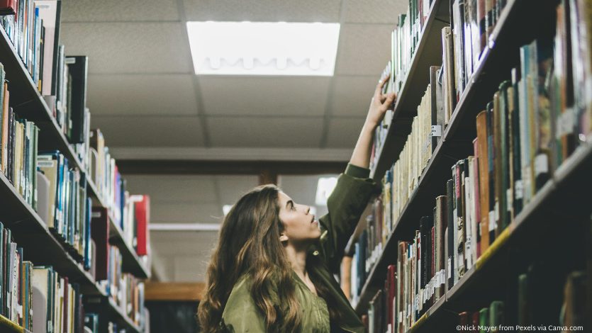 Woman reaching for book on shelf