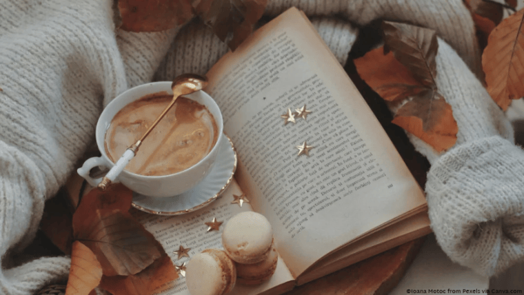 An open book on a cozy sweater with a cup of tea on top